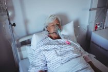 Senior patient lying on bed with oxygen mask on face in hospital — Stock Photo
