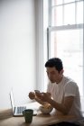 Людина за допомогою мобільного телефону в будинку маючи сніданок — стокове фото
