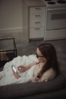 Mulher usando telefone celular no sofá em casa — Fotografia de Stock