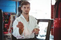 Retrato del jugador de karate realizando postura de karate en el gimnasio - foto de stock