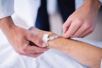 Médecin attachant iv goutte à goutte sur les patients main à l'hôpital — Photo de stock