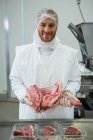 Retrato de açougueiro segurando carne crua na fábrica de carne — Fotografia de Stock