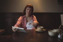 Mitte erwachsene Frau mit kleiner Tochter nutzt digitales Tablet im Café — Stockfoto