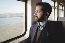 Homem de negócios atencioso olhando através da janela do trem — Fotografia de Stock