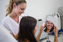 Счастливая женщина, проверяющая кожу в зеркале после косметического лечения — стоковое фото