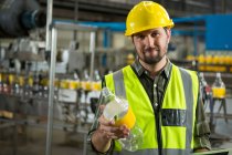 Retrato de trabalhador masculino confiante inspecionando garrafas na fábrica de suco — Fotografia de Stock