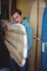 Young man selecting surfboard in a shop — Stock Photo