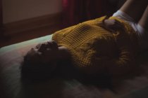 Orientalische Frau im gelben Pullover schläft zu Hause auf dem Bett — Stockfoto