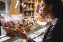 Mulher selecionando salsicha no balcão de carne no supermercado — Fotografia de Stock