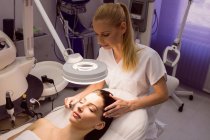 Dermatóloga femenina realizando depilación láser en cara de paciente en clínica - foto de stock