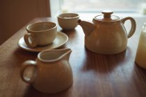 Tetera y taza de café en la mesa de madera en la cafetería - foto de stock