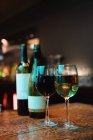 Окуляри червоного і білого вина і пляшки на барній стійці в барі — стокове фото