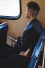Бізнесмен з цифровим планшетом і посилкою, що подорожує в поїзді — стокове фото