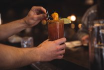 Крупним планом бармен тримає коктейль за барною стійкою — стокове фото