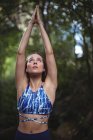 Donna che esegue yoga nella foresta in una giornata di sole — Foto stock
