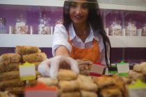 Жінка-торговець організовує турецькі солодощі за лічильником в магазині — стокове фото