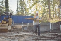 Строитель, перевозящий древесину на строительной площадке — стоковое фото