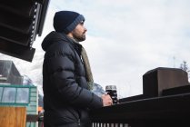 Чоловік в зимовому одязі тримає пивний келих на відкритій терасі — стокове фото