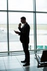 Empresario tomando café mientras usa tableta digital en la sala de espera en el aeropuerto - foto de stock