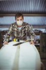 Frontansicht eines Mannes, der in der Werkstatt Surfbretter bastelt — Stockfoto