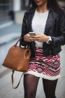 Жінка використовує мобільний телефон під час ходьби в офісних приміщеннях — стокове фото