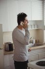 Homem falando no celular na cozinha em casa — Fotografia de Stock