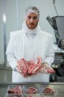 Portrait of butcher holding raw meat at meat factory — Stock Photo
