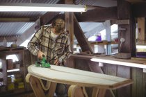 Man using modified planer in surfboard workshop — Stock Photo