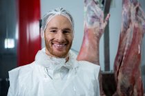 Retrato del carnicero sonriendo en cámara en fábrica de carne - foto de stock