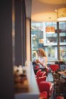 Mulher de negócios loira sentada com café e smartphone no balcão na cafetaria — Fotografia de Stock