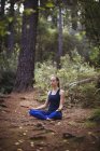 Woman performing yoga in forest on a sunny day — Stock Photo