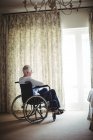 Пенсионер сидит на инвалидной коляске в спальне дома — стоковое фото