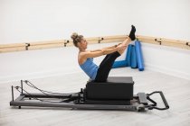 Woman exercising on reformer equipment in gym — Stock Photo
