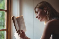 Bella donna che legge libro a casa — Foto stock
