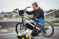 Велогонщик ремонтирует велосипед BMX в скейтпарке — стоковое фото