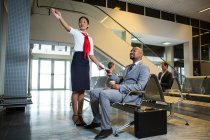 Female staff showing direction to businessman at airport terminal — Stock Photo