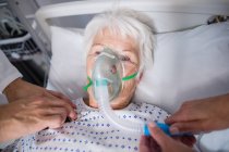 Doctors examining senior patient with stethoscope in hospital bed — Stock Photo