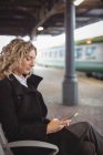Femme d'affaires adulte moyenne utilisant un smartphone sur la plate-forme ferroviaire — Photo de stock