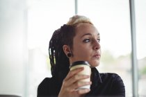 Frau hält Einweg-Kaffeetasse in Café — Stockfoto