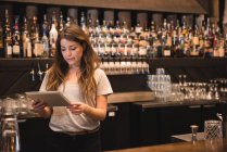 Barkeeperin mit digitalem Tablet am Tresen — Stockfoto