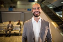 Geschäftsmann lächelt am Flughafen in die Kamera — Stockfoto