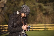 Visão traseira da mulher olhando para fotos na câmera digital em um dia ensolarado — Fotografia de Stock