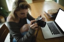Donna che guarda le immagini sulla fotocamera digitale in soggiorno a casa — Foto stock