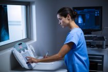 Enfermera tomando notas en sala de rayos X en el hospital - foto de stock