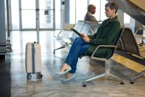 Mujer usando tableta digital mientras está sentado en la terminal del aeropuerto - foto de stock