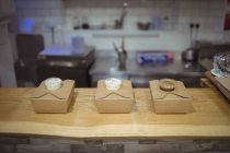 Drei Schachteln mit verpackten Mahlzeiten und Soßen auf dem Holztisch am Restauranttisch — Stockfoto
