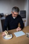 Людина, використовуючи цифровий планшетний в будинку маючи сніданок — стокове фото