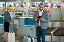Homme d'affaires avec bagages enregistrant sa carte d'embarquement au terminal de l'aéroport — Photo de stock