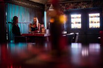 Schöne Frauen interagieren, während sie Wein in der Bar trinken — Stockfoto