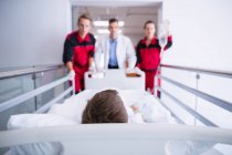 Médecins poussant lit civière d'urgence dans le couloir à l'hôpital — Photo de stock